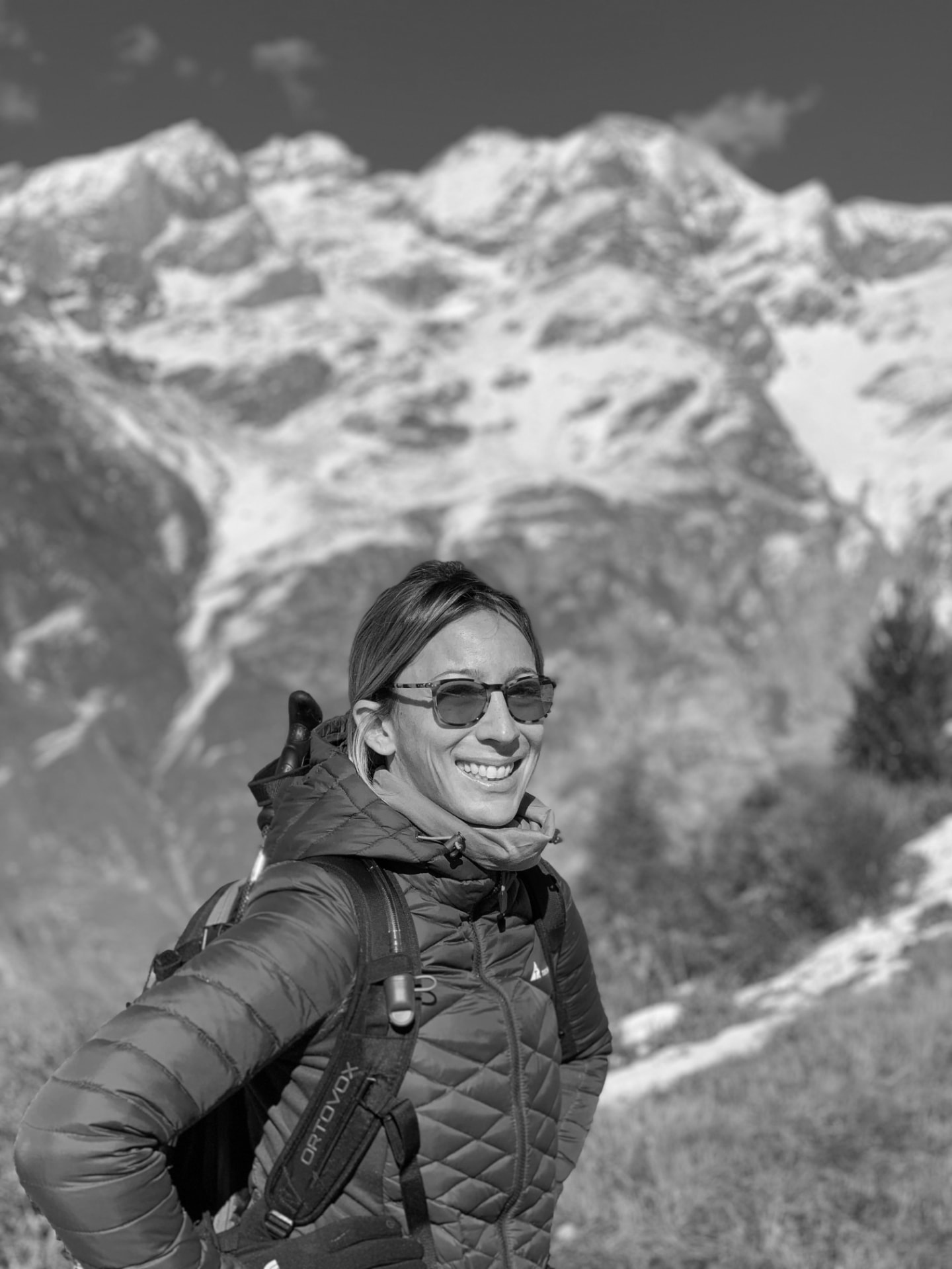 Claire Owen smiling in the Alps, with snow-covered mountains behind her